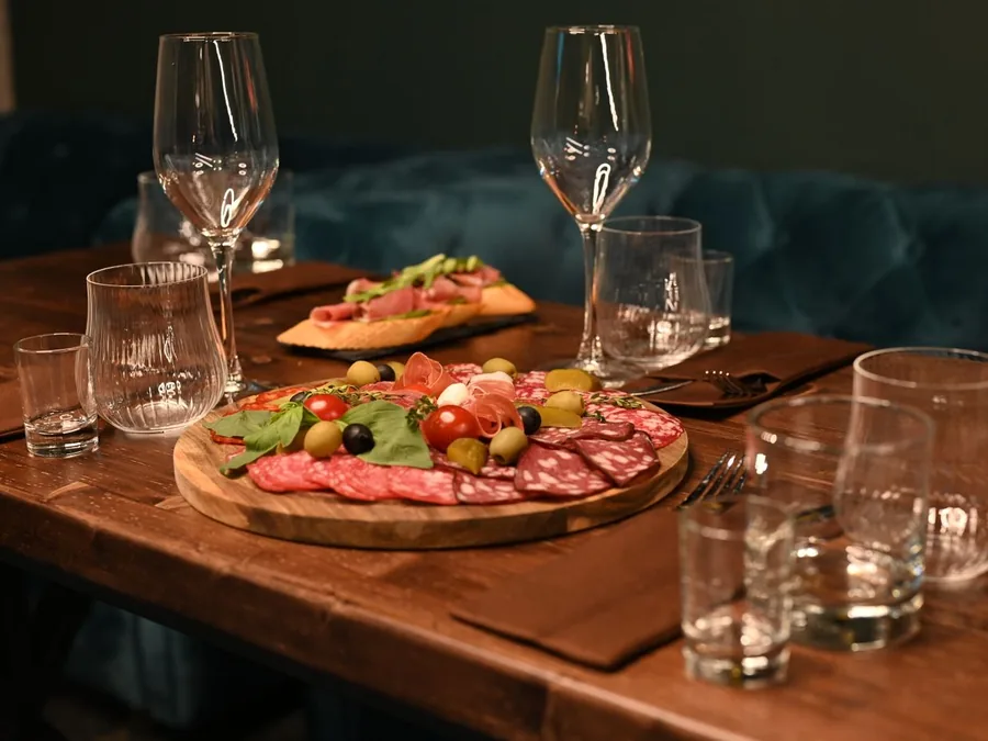 Planche d'apéro garnie de charcuterie et verres posés sur une table en bois